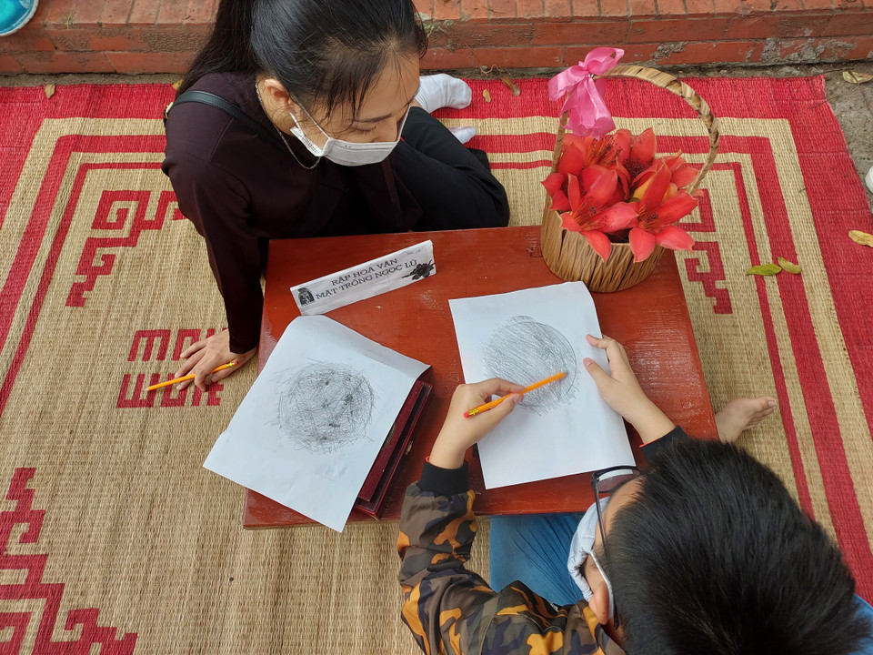 Em Hoàng An (8 tuổi) được học cách in rập mặt trống đồng.(Ảnh: Minh Thu/Vietnam+)