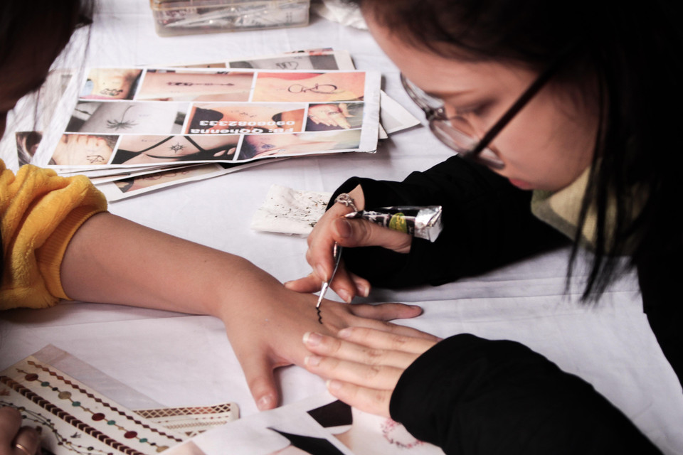 Trong khi các bạn trẻ lại say sưa với trò vẽ henna. (Ảnh: PV/Vietnam+)