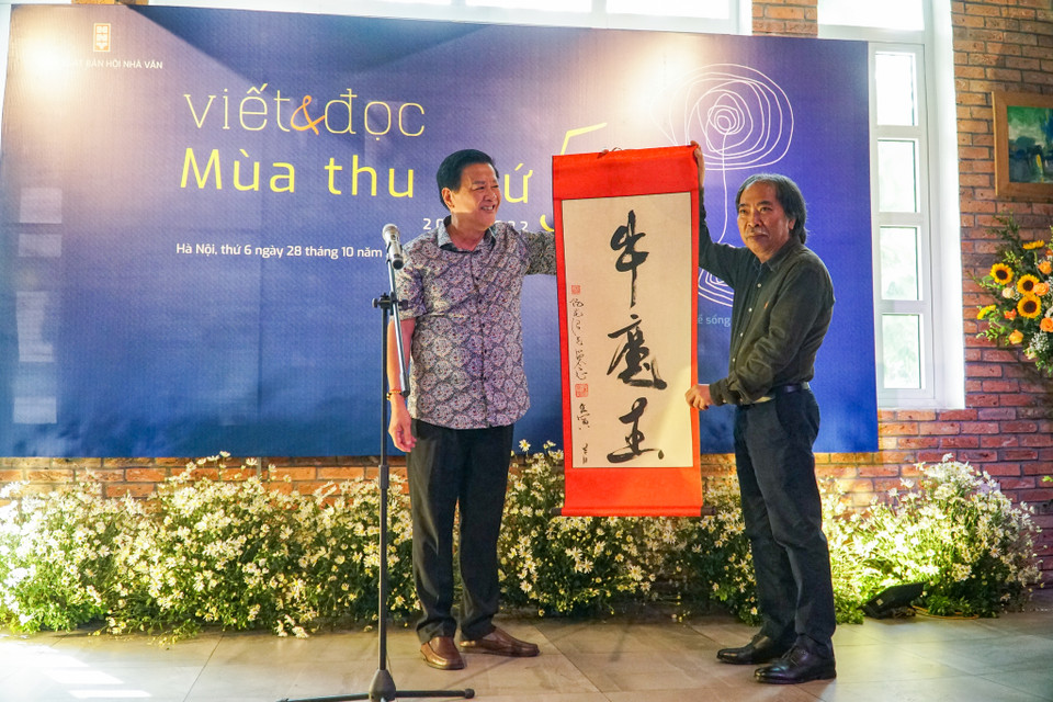 Doanh nhân Phó Đức An (trái), tác giả bộ sách “Đường đời” tặng bức thư pháp cho nhà thơ Nguyễn Quang Thiều. (Ảnh: Hoàng Hiếu/Vietnam+) 