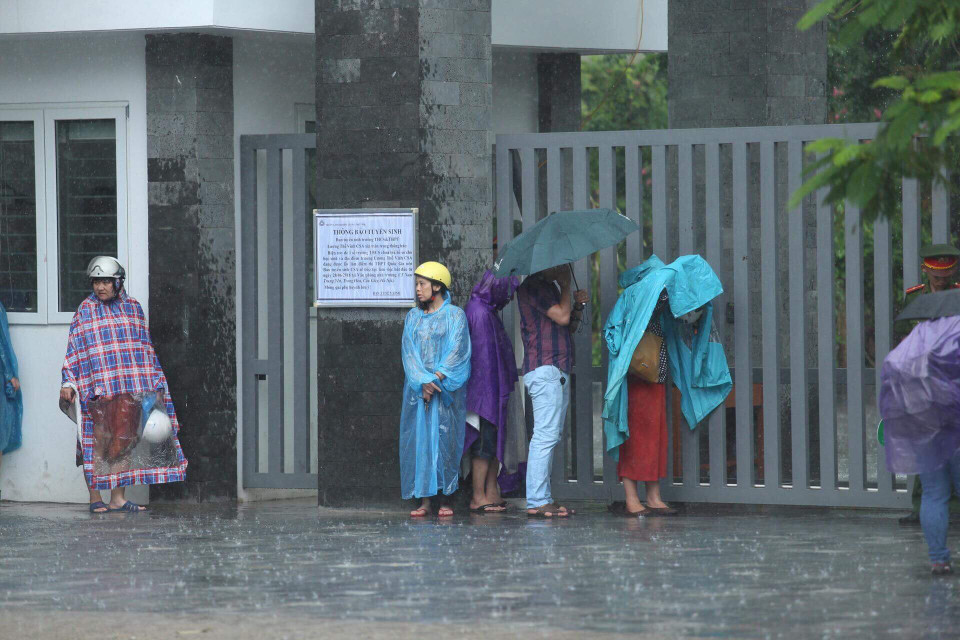 Nhiều phụ huynh đứng nép vào tường để tránh mưa... (Ảnh: Sơn Bách/Vietnam+)