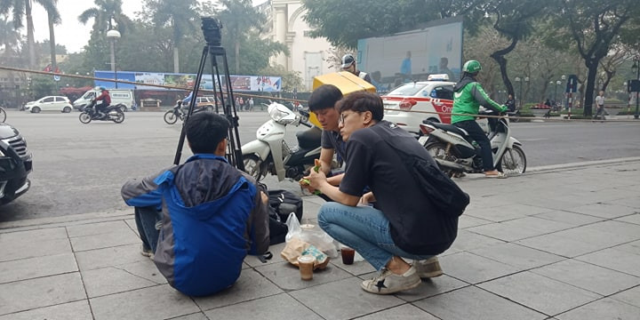 Phóng viên tranh thủ nghỉ ngơi, ăn trưa, trong lúc chờ đưa tin. (Ảnh: Mạnh Hùng/Vietnam+)
