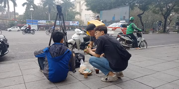 Phóng viên tranh thủ nghỉ ngơi, ăn trưa, trong lúc chờ đưa tin. (Ảnh: Mạnh Hùng/Vietnam+) 