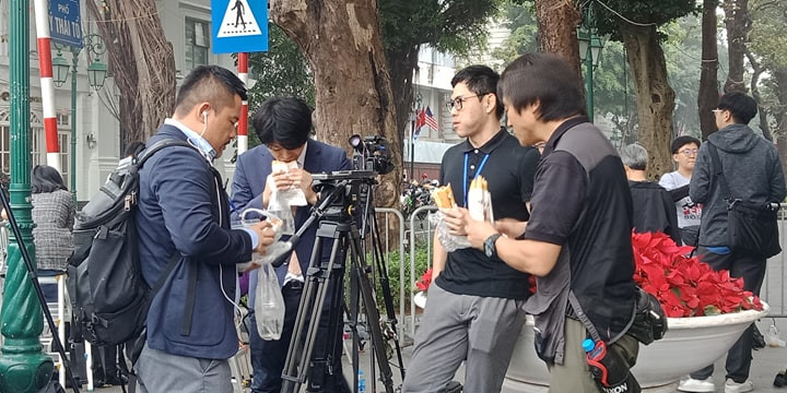 Nhiều phóng viên quốc tế đã chọn bánh mì kẹp để làm bữa trưa giản dị trong lúc chờ đưa tin. (Ảnh: Mạnh Hùng/Vietnam+)