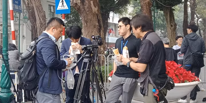Nhiều phóng viên quốc tế đã chọn bánh mì kẹp để làm bữa trưa giản dị trong lúc chờ đưa tin. (Ảnh: Mạnh Hùng/Vietnam+)