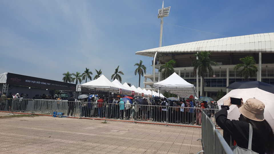  Bạn Việt Thắng (Hà Nội) cũng gặp rắc rối tương tự. Thắng có vé ngồi khu CAT 1 tối 30/7 (6,8 triệu đồng/vé). Ban tổ chức bố trí hai quầy CAT 1 cho hai đêm diễn 29/7 và 30/7 cạnh nhau. Do không có người hướng dẫn nên Thắng đã xếp hàng ở quầy CAT 1 của đêm 29/7. Khi biết mình nhầm thì phải quay lại xếp hàng từ đầu ở quầy CAT 1 của đêm 30/7, lãng phí cả tiếng đồng hồ dưới trời nắng. (Ảnh: PV/Vietnam+) 