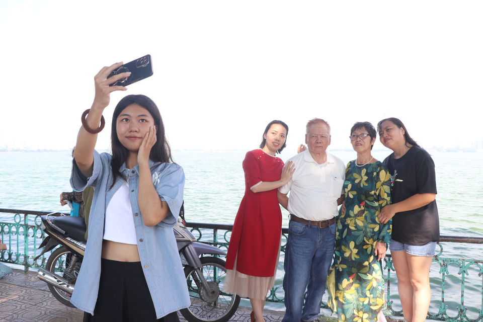Gia đình chọn thư giãn, đi ăn kem và chụp ảnh kỷ niệm tại Hồ Tây. (Ảnh: Minh Anh/Vietnam+)