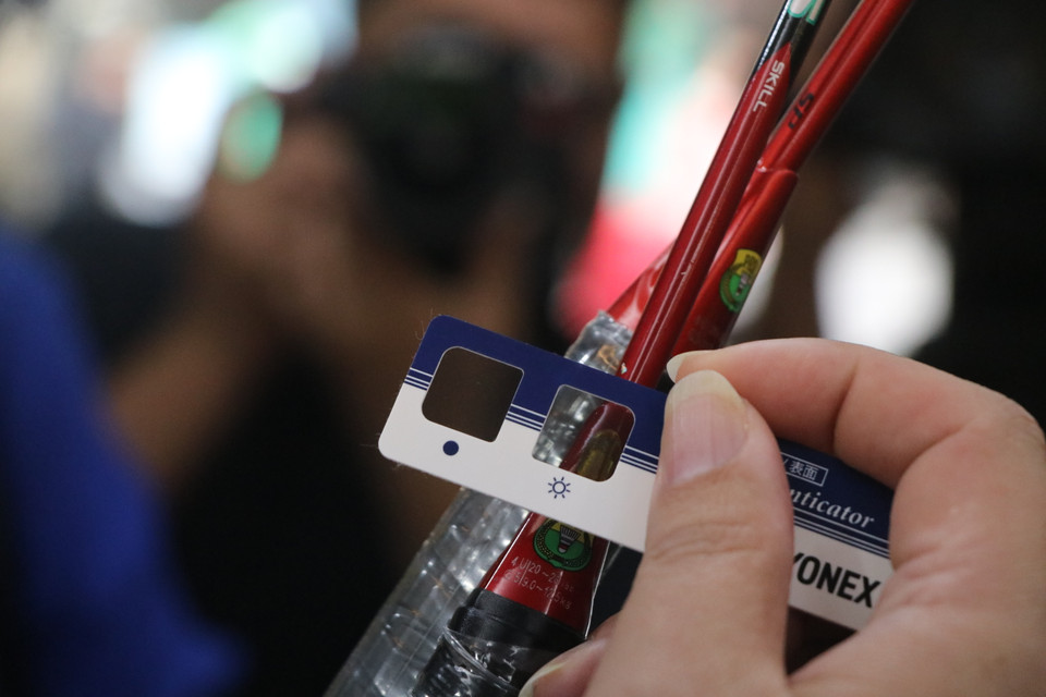 Tương tự cũng có những dụng cụ khác như chiếc kính kiểm tra đổi màu đối với tem giả, tem thật trên mặt hàng vợt cầu lông. Người tiêu dùng được khuyến cáo đến các cửa hàng chính hãng để được hướng dẫn kiểm tra như thế này. (Ảnh: Minh Anh/Vietnam+)