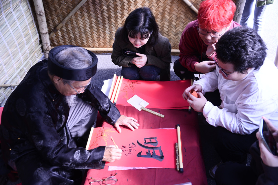 Sinh viên quốc tế Trường Đại học Hà Nội với trải nghiệm hồi hộp chờ tới lượt xin chữ ông đồ, nét đẹp văn hóa truyền thống đầu năm mới của người Việt... (Ảnh: PV/Vietnam+)