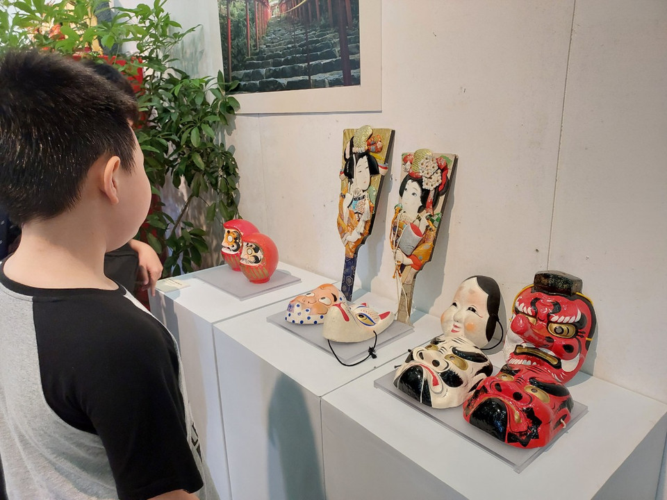 Một em nhỏ say sưa ngắm nhìn những món đồ chơi truyền thống bằng gỗ. (Ảnh: Minh Thu/Vietnam+)