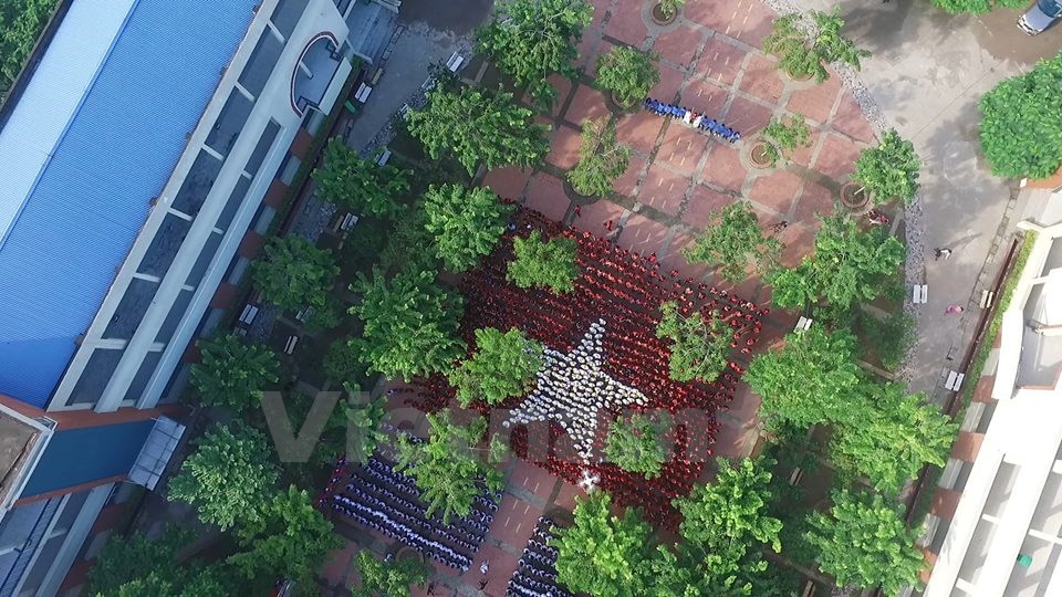 Những bài học ấy thấm vào học trò qua những hành động cụ thể, như cùng nhau xếp hình lá cờ Tổ quốc trong ngày khai trường. (Ảnh: Tùng Lâm/Vietnam+)