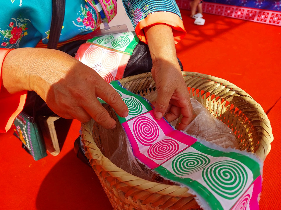 Bà khoe những tấm vải mới thêu có hoa văn sặc sỡ. (Ảnh: Minh Thu/Vietnam+)