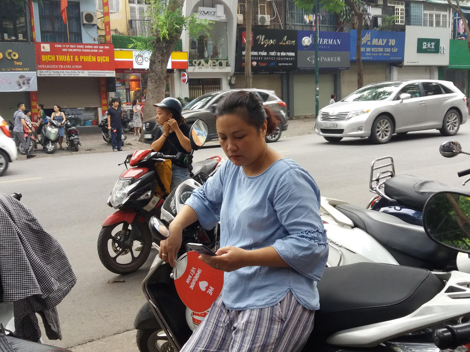 Phía bên ngoài cổng trường, các bậc phụ huynh bắt đầu nhìn đồng hồ và ngóng chờ đến hết giờ thi. (Ảnh: PM/Vietnam+)