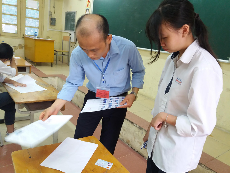 Giám thị kiểm tra kỹ càng các vật dụng thí sinh mang theo. (Ảnh: PM/Vietnam+)