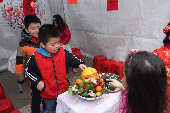 Mỗi lớp được bố trí một gian nhà nhỏ. Trong khi các bạn gói bánh, một số học sinh được giao nhiệm vụ trang trí ngôi nhà của lớp mình như bày mâm ngũ quả. (Ảnh: CTV/Vietnam+)