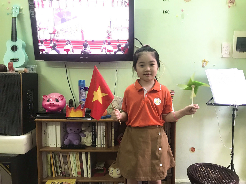 Học sinh Trường Tiểu học Hoàng Hoa Thám, quận Đống Đa, Hà Nội, dù khai giảng qua truyền hình vẫn chuẩn bị sẵn cờ nhỏ cầm tay. (Ảnh: CTV/Vietnam+)