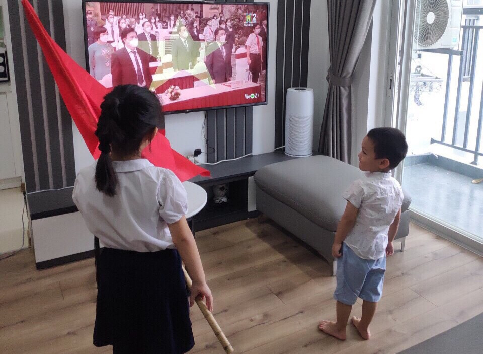 Học sinh thậm chí còn được phụ huynh chuẩn bị hẳn lá cờ to để vẫy. (Ảnh: CTV/Vietnam+)