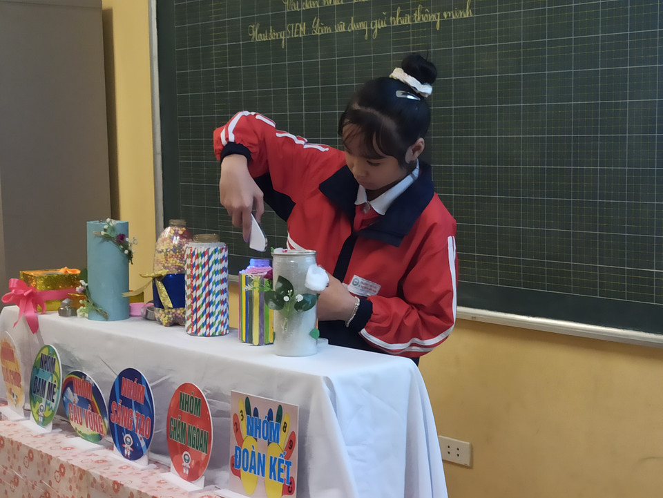 Một học sinh đo nhiệt độ của các bình sau khi các nhóm trình bày xong để tìm ra sự khác nhau trong khả năng truyền nhiệt của các nguyên liệu. (Ảnh: PM/Vietnam+)