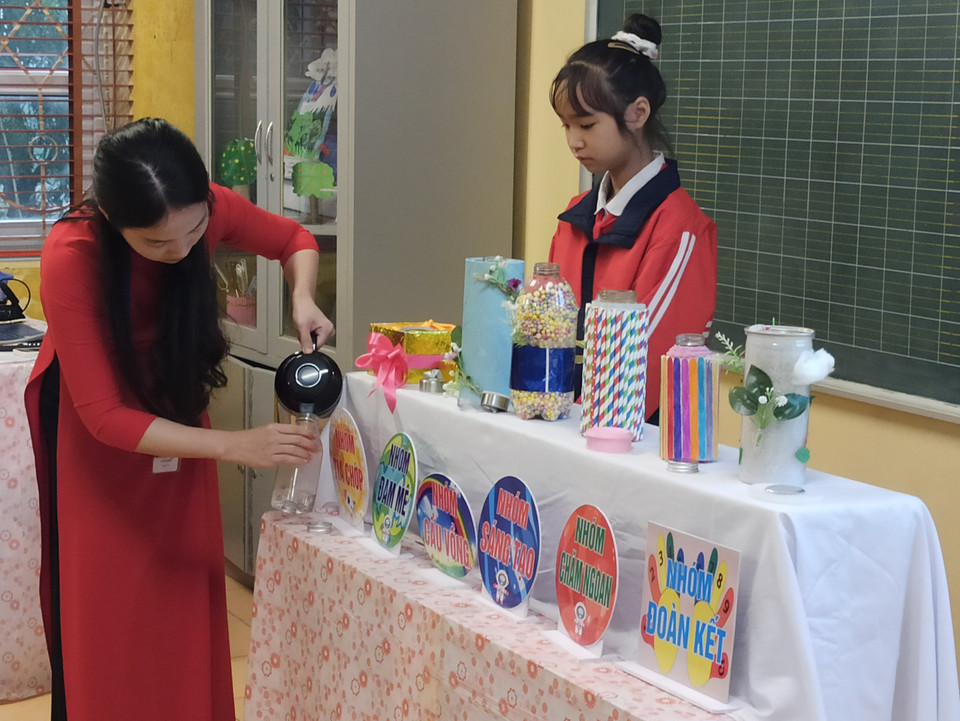 Cả lớp hồi hộp chờ đợi màn kiểm tra khả năng giữ nhiệt của các bình. Cô Lan Phương cẩn thận đổ nước nóng vào chai thủy tinh để đối sánh…(Ảnh: PM/Vietnam+)