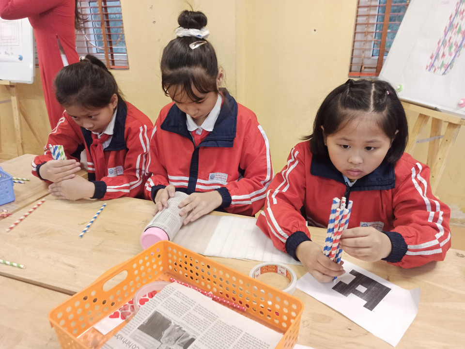 Nhóm khác lại dùng giấy báo, xốp bên trong, trang trí bằng que gỗ và ống hút giấy sặc sỡ bên ngoài. (Ảnh: PM/Vietnam+)