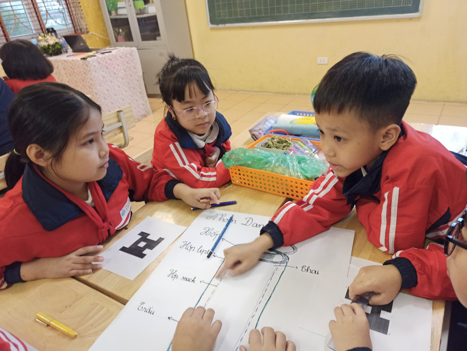 Khác với lớp học truyền thống, các bàn được kê lại để học sinh ngồi quây thành từng nhóm. Mỗi nhóm đều được đặt tên riêng và say sưa thảo luận ý tưởng. (Ảnh: PM/Vietnam+)