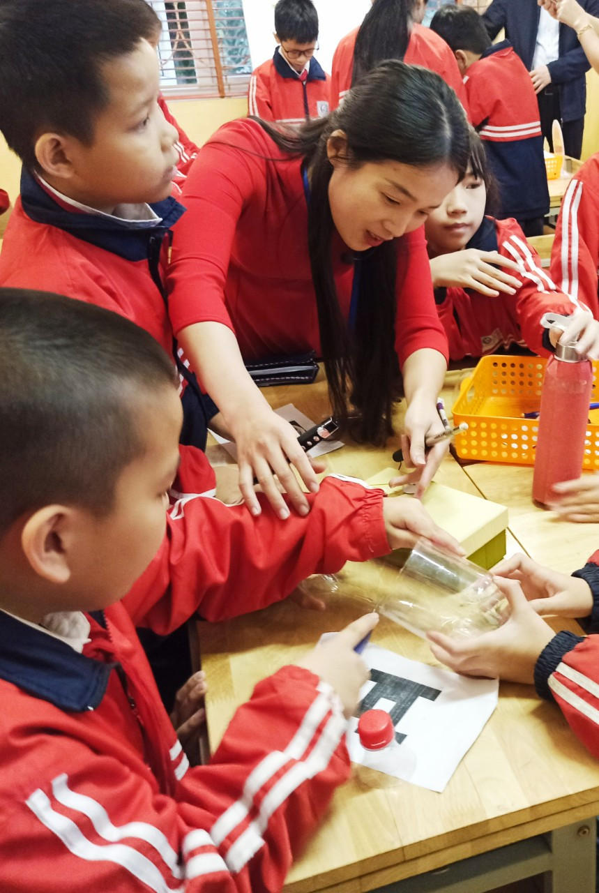 Các nhóm bắt tay vào thực hành, biến ý tưởng thành sản phẩm. Cô Lan Phương cẩn thận nhắc nhở và hỗ trợ các con các công đoạn khó, cần sử dụng dao. (Ảnh: PM/Vietnam+)