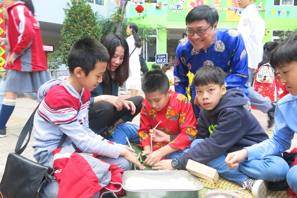 Thầy Bình thích thú xem học trò tập gói bánh chưng. (Ảnh: PV/Vietnam+)