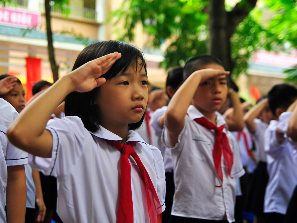 Đeo khăn quàng đỏ, các em nghiêm trang trong lễ chào cờ. (Ảnh: Võ Phương/Vietnam+)