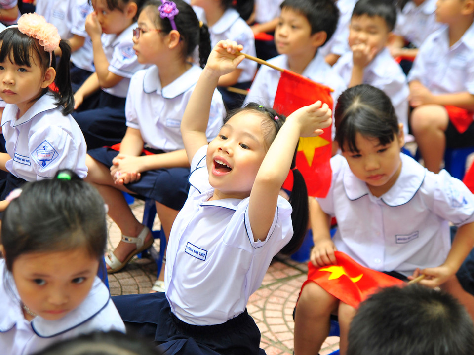  Mặc bộ đồng phục mới, tay cầm cờ, cô học trò nhỏ này rất hào hứng trước không khí tưng bừng của ngày khai trường. (Ảnh: Võ Phương/Vietnam+)