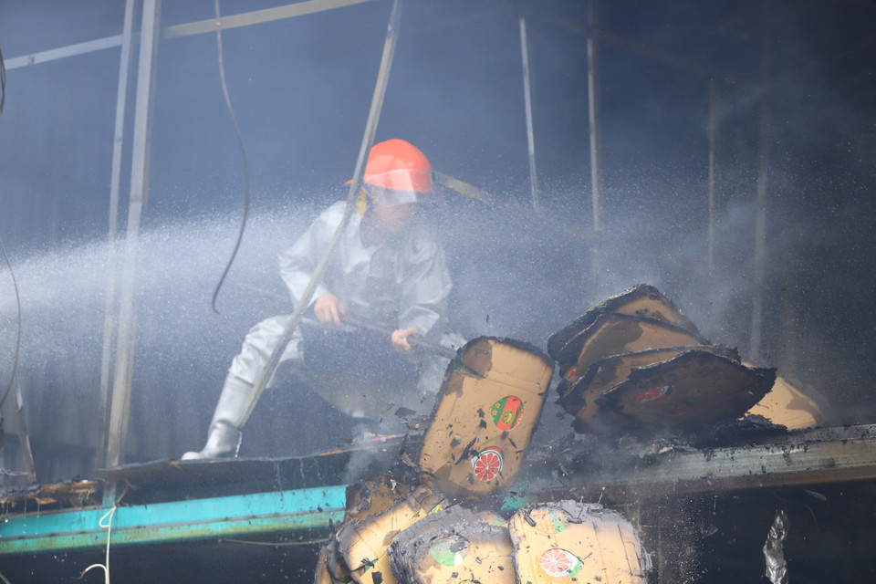 Tại hiện trường, lực lượng chức năng đã huy động máy xúc đến phá dỡ mái tôn, tường để tiếp cận bên trong. (Ảnh: PV/Vietnam+)