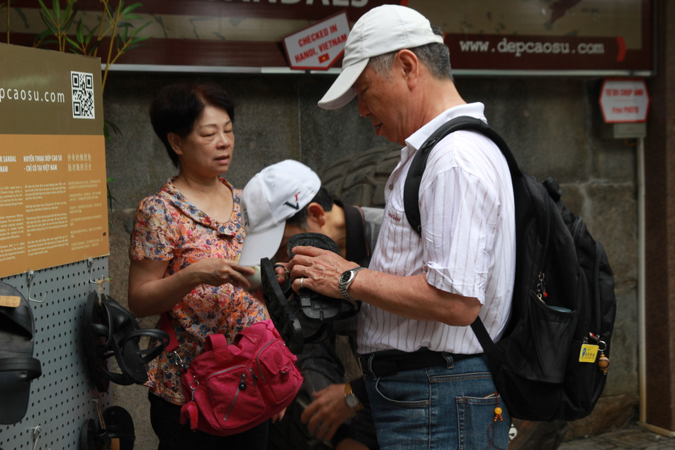 Du khách người Trung Quốc ‘chiêm ngưỡng’ đôi dép lốp tại gian hàng của Vua dép lốp Phạm Quang Xuân. (Ảnh: Mai Hiền/Vietnam+)