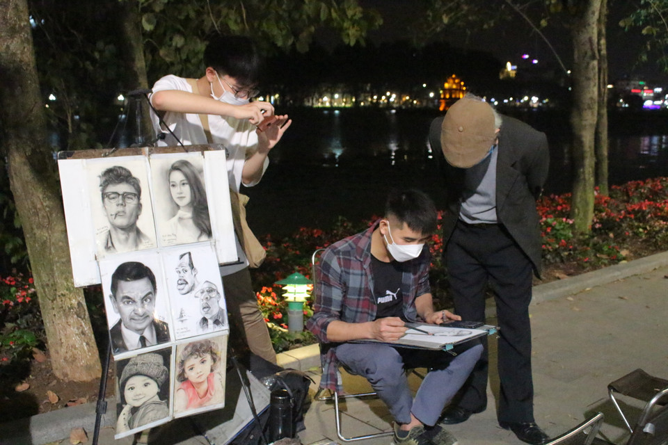 Anh Tùng Sơn, họa sỹ có 10 năm vẽ truyền thần tại khu vực Hồ Gươm, nhận xét lượng người đổ lên phố đi bộ vào thời điểm 19 giờ hôm nay đông hơn so với thứ Sáu thông thường của thời điểm trước dịch. (Ảnh: Minh Anh/Vietnam+)