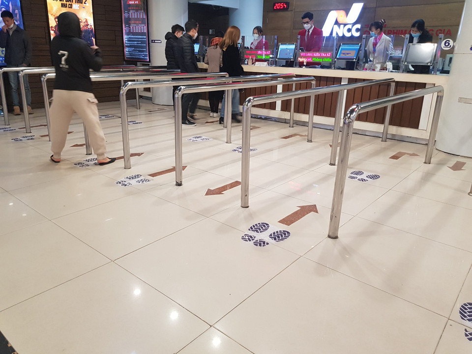 Rạp cũng đã có những hình thức hướng dẫn để khách hàng chủ động giữ khoảng cách đồng thời bố trí nhân viên ngồi ở cửa để chủ động xịt khuẩn, nhắc nhở quét mã truy vết. (Ảnh: Minh Anh/Vietnam+)