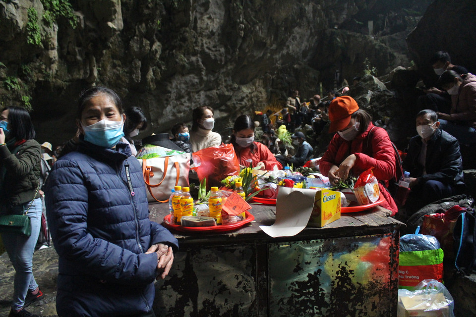 Phần lớn người dân khi cúng lễ trong động đều tuân thủ việc đeo khẩu trang, khi sắp đồ lễ cũng cố gắng chỉ tập trung với người cùng đoàn thay vì đứng cùng nhiều người khác đoàn. (Ảnh: Minh Anh/Vietnam+)