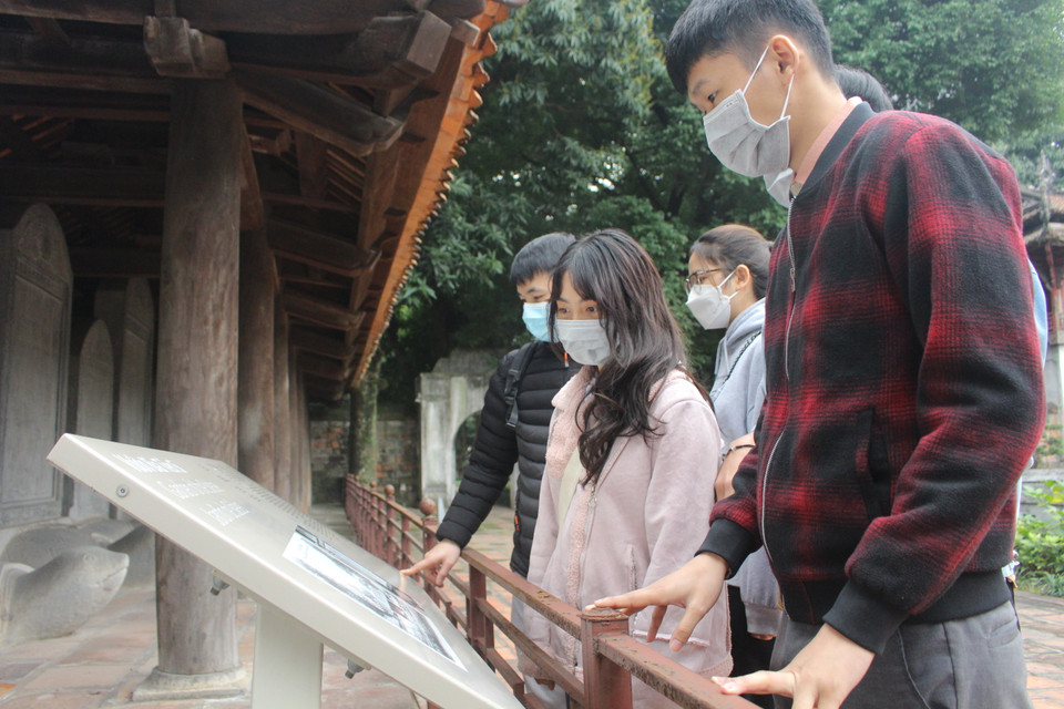 Nhóm sinh viên đại học này vừa từ quê trở lại Thủ đô, chọn kết hợp giữa hai việc tham quan và cầu may mắn tại Văn Miếu. Các em thể hiện thái độ thích thú trải nghiệm hệ thống thuyết minh tự động qua quét mã QR trên điện thoại. (Ảnh: Minh Anh/Vietnam+)