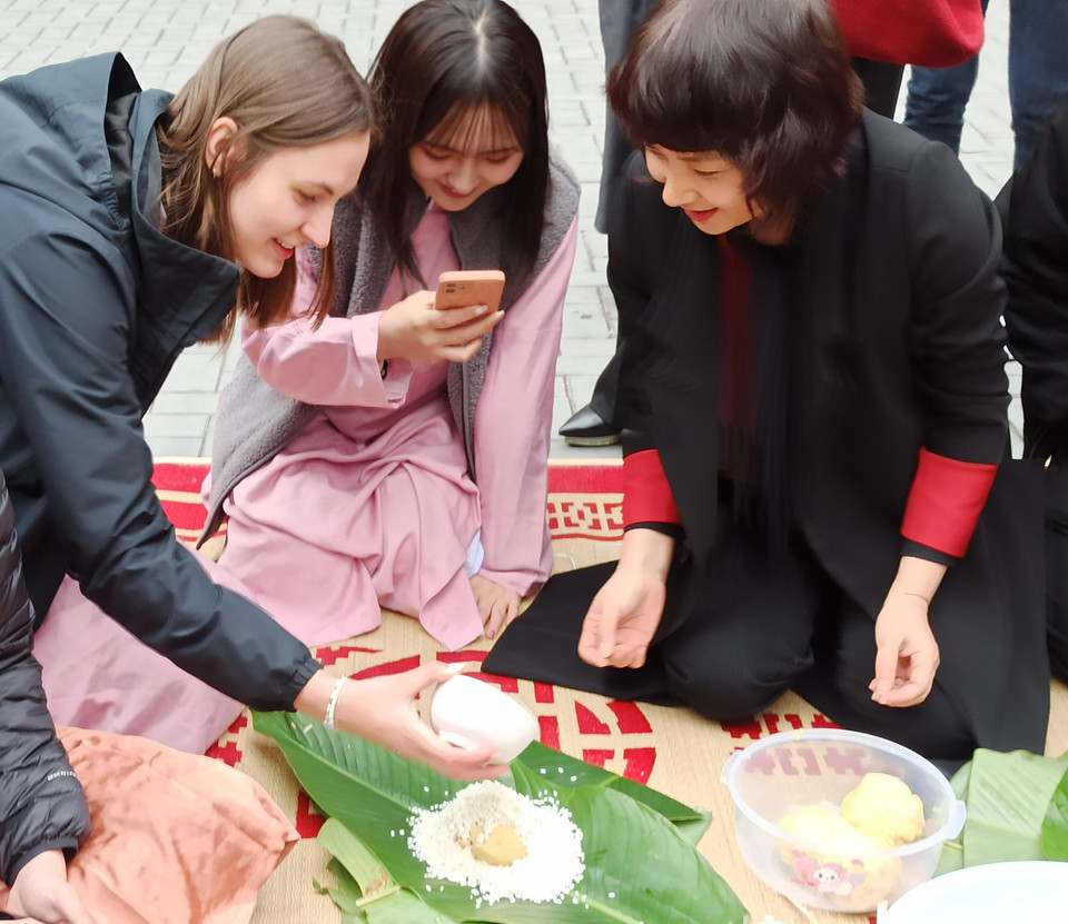 Phó giáo sư Phạm Thu Hương, Phó hiệu trưởng Trường Đại học Ngoại thương hướng dẫn sinh viên quốc tế gói bánh chưng… (Ảnh: PV/Vietnam+).