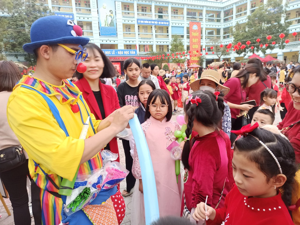 Chiều nay, 3/2, Trường Tiểu học Chu Văn An (Hoàng Mai, Hà Nội) đã tổ chức trải nghiệm chợ Tết cho học sinh. Cả sân trường rực trong sắc đỏ. Hình ảnh chú hề với những chùm bóng bay sặc sỡ đã trở thành hình ảnh quen thuộc trong những phiên chợ Tết truyền thống và thu hút đông đảo học sinh. (Ảnh: PV/Vietnam+)
