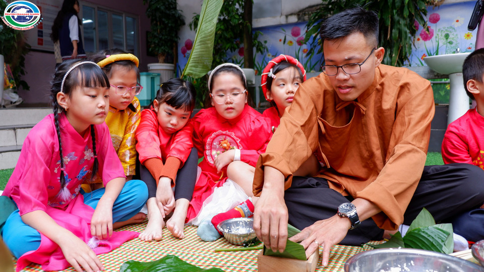 Trước đó, Trường Trường Tiểu học I-sắc Niu-tơn cũng đã tổ chức nhiều hoạt động trải nghiệm Tết Nguyên đán truyền thống cho học sinh. Trong ảnh, các học sinh chăm chú theo dõi thầy giáo hướng dẫn gói bánh chưng... (Ảnh: PV/Vietnam+)