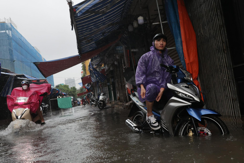 Lượng nước ngập sâu khiến lưu thông qua khu vực này vô cùng vất vả. (Ảnh: Minh Sơn/Vietnam+)