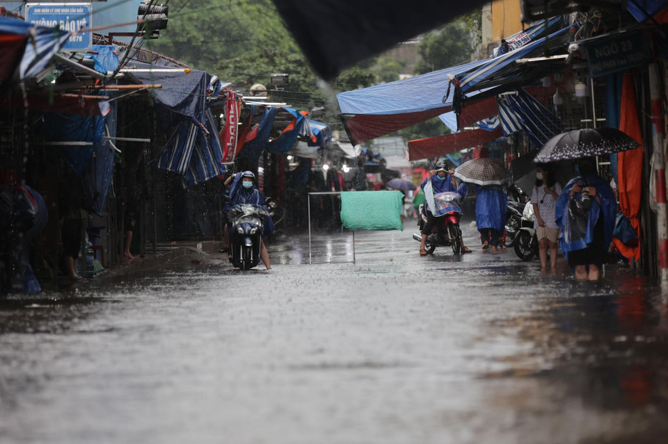 Cơn mưa lớn từ ngày 11/8 tại Hà Nội khiến cuộc sống của người dân bị đảo lộn. Tại khu vực Chợ Xanh, quận Cầu Giấy, có đoạn trũng ngập lớn gây cản trở đi lại. (Ảnh: Minh Sơn/Vietnam+)
