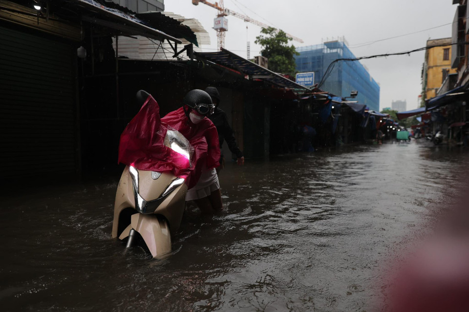 Nhiều người tham gia giao thông gặp hiện tượng chết máy, phải chấp nhận lội nước để dắt ra khỏi vùng ngập. (Ảnh: Minh Sơn/Vietnam+)