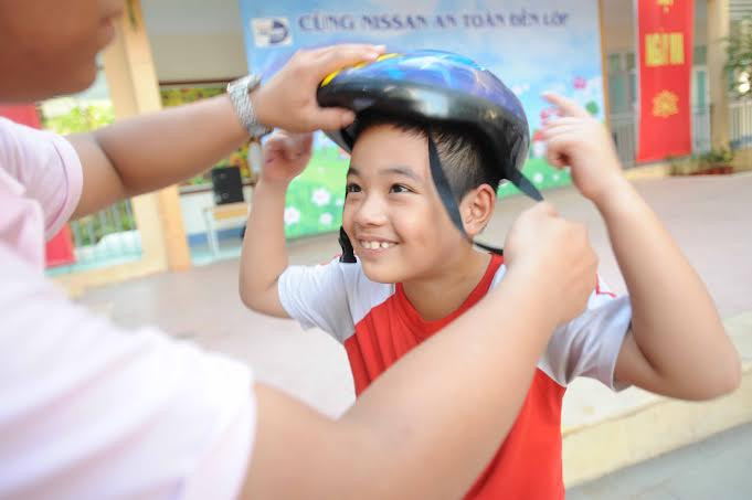 Các em cũng được hướng dẫn cách sử dụng và cài quai mũ bảo hiểm đúng cách trước khi thực hành. (Ảnh: CTV/Vietnam+)