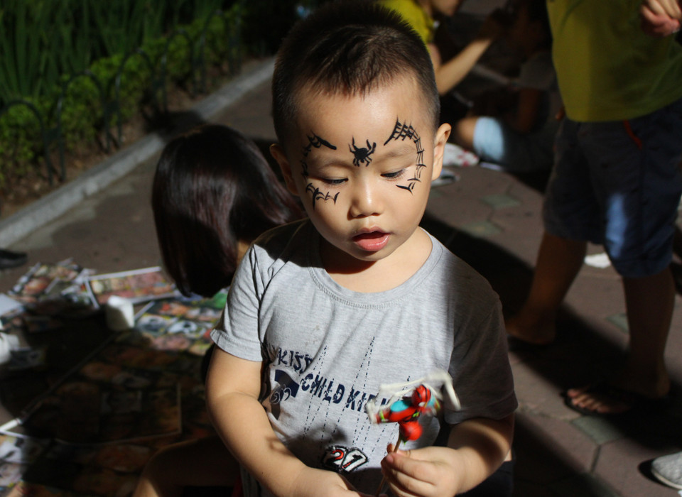 Các em nhỏ cũng rất hào hứng khi được bố mẹ cho vẽ mặt nạ để đi chơi Halloween. (Ảnh: Lê Thu Hà/Vietnam+)