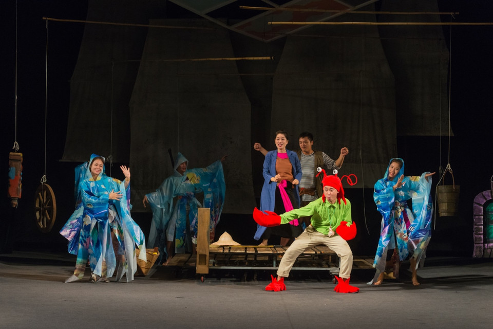 Đạo diễn cho biết, những video trò chuyện của thiếu nhi hai nước Việt-Đức (về những mong muốn cũng như quan niệm của các em về hạnh phúc) được sử dụng lồng ghép trong đó là điểm nhấn riêng, mang tới hơi thở đương đại cho bản dựng này. Một người kể chuyện trong hình hài con tôm hùm sẽ gắn kết các nhân vật trong vở diễn với nhân vật trong video. (Ảnh: BTC)