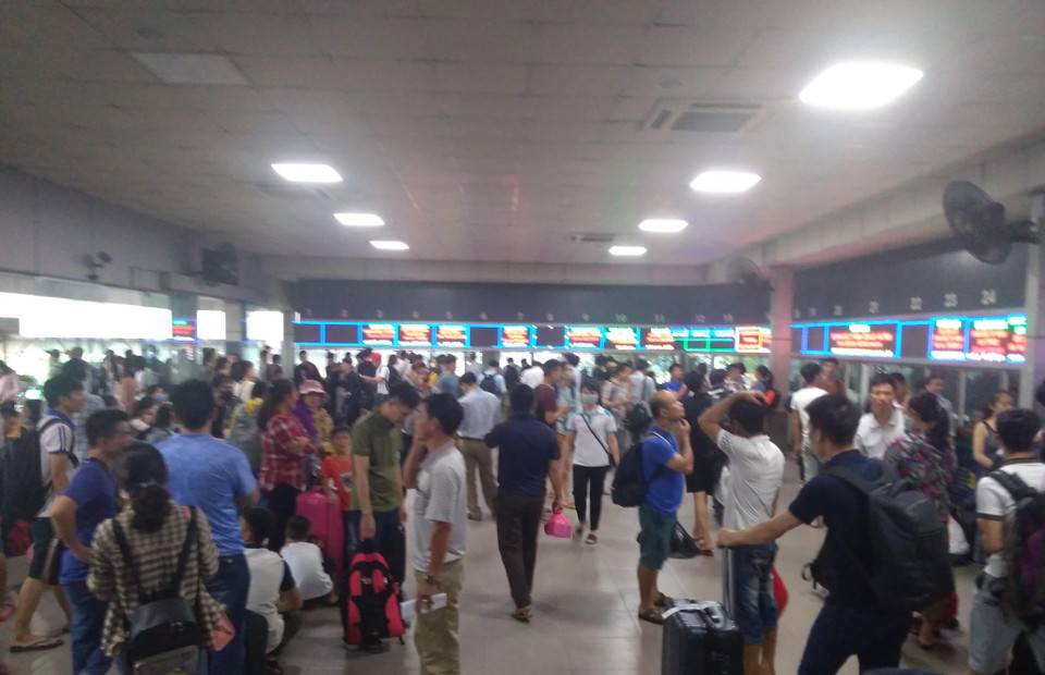 Lượng khách đông, khu vực nhà chờ Bến xe Nước Ngầm chật kín người, phía bên ngoài, nhiều người còn đội mưa do ảnh hưởng từ cơn bão số 4. (Ảnh: Anh Thùy/Vietnam+)