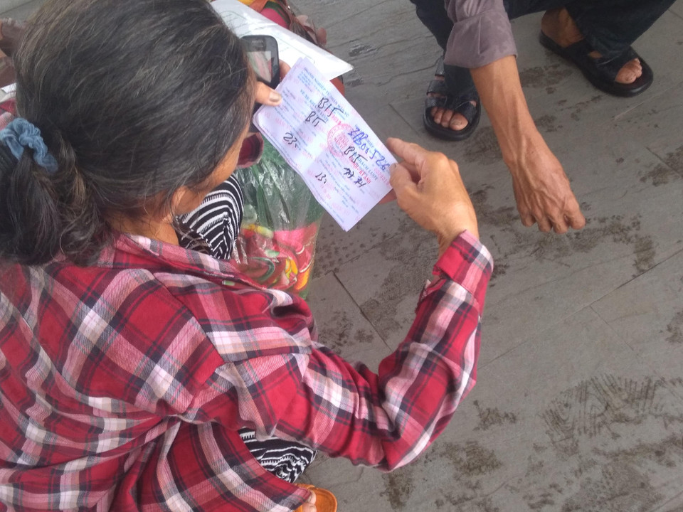 Sau khi xếp hàng và mua được vé, nhưng vẫn chưa đến giờ lên xe, người phụ nữ sốt ruột chờ đợi. (Ảnh: Anh Thùy/Vietnam+)