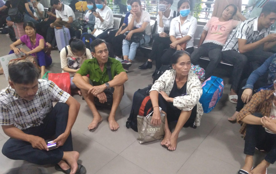 Không đủ ghế, người dân mệt mỏi ngồi bệt chờ xe. (Ảnh: Anh Thùy/Vietnam+)