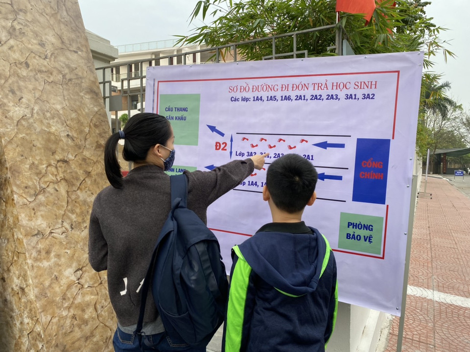 Các lối đi đón, trả học sinh tại Trường Tiểu học Hoàng Mai đều được phân luồng rõ ràng tránh tụ tập đông người. Trong ảnh, một phụ huynh dặn dò con lối đi để thực hiện nội quy của nhà trường. (Ảnh: PV/Vietnam+)