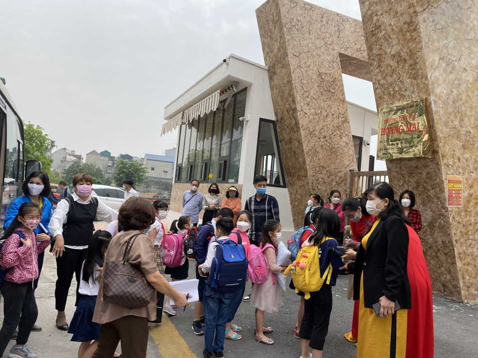 Tại trường Tiểu học Hoàng Mai, Ban giám hiệu, giáo viên trong tà áo dài truyền thống có mặt ở cổng trường từ rất sớm đón các con lần đầu tiên tới ngôi trường mới. Hiệu trưởng nhà trường cho biết đã cố gắng bố trí cho các con học bán trú để cha mẹ có thể yên tâm làm việc. (Ảnh: PV/Vietnam+)