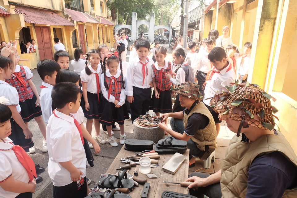 Các em học sinh tìm hiểu về cách làm ra đôi dép cao su đã gắn bó với Bác Hồ, với những chiến sỹ trong suốt chiều dài đấu tranh khốc liệt của dân tộc. (Ảnh: Phương Anh/Vietnam+)
