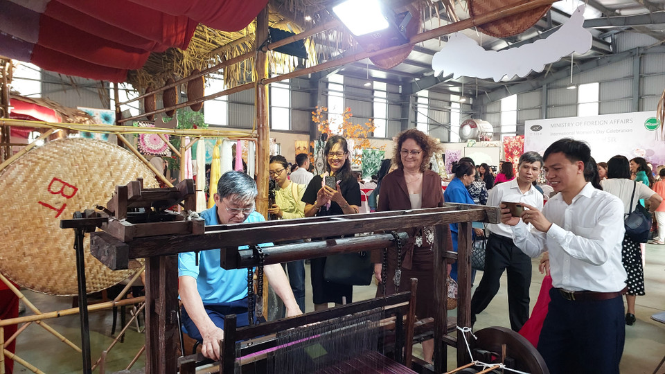 Các đại biểu quan sát nghệ nhân thao tác trên máy dệt thoi. (Ảnh: Minh Thu/Vietnam+)